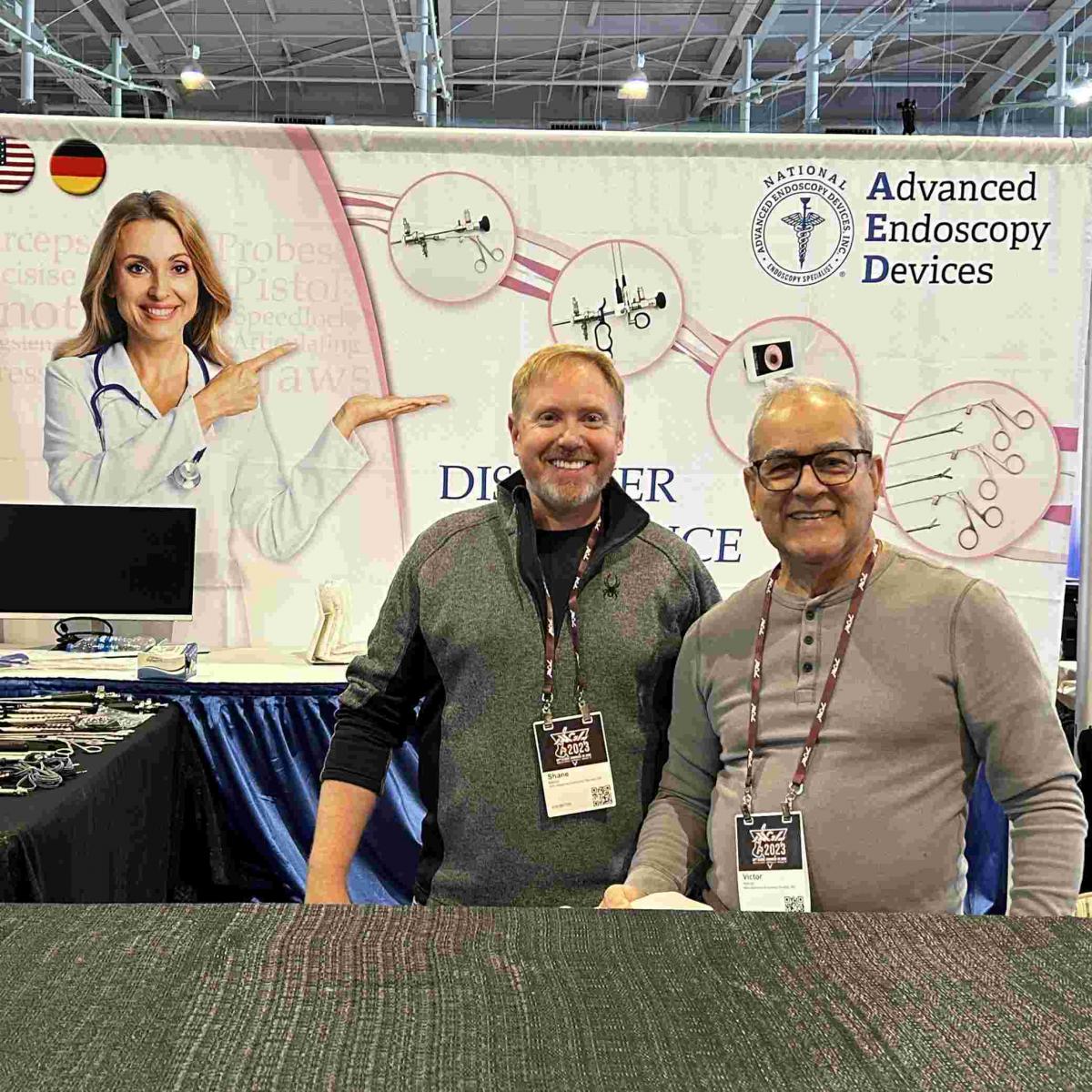 Advanced Endoscopy Devices at AAGL 2023 Photos Nashville - Two men taking a photo infront of banner